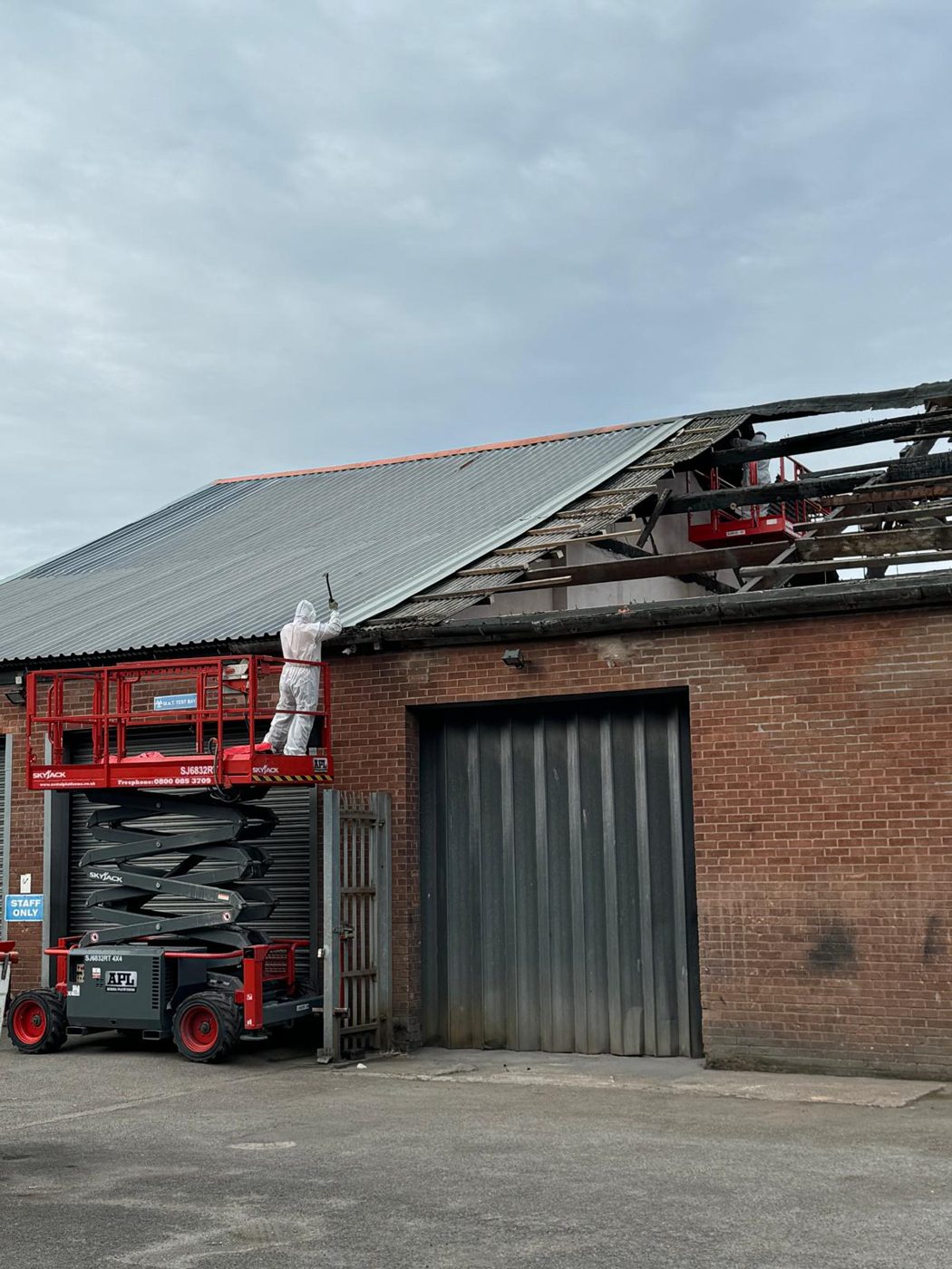 Brick industrial unit in Manchester with damaged roof and a scissor lift